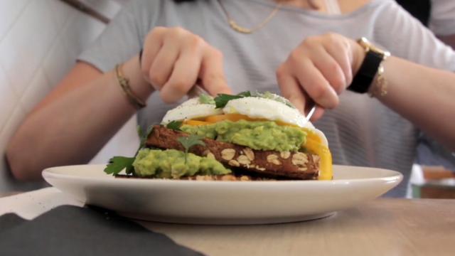 Žena se sprema da iseče tost sa avokadom i jajima