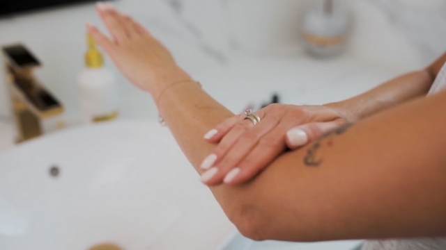Žena maže kremu na ruku, kako bi negovala kožu pre uklanjanja tetovaže