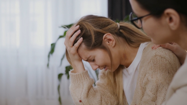 Terapeut smireno pruža podršku ženi koja plače i drži glavu