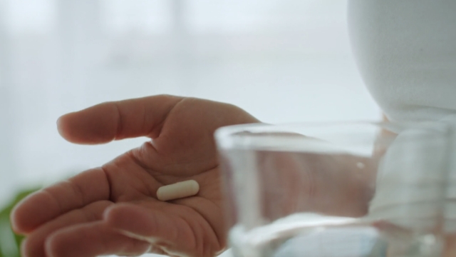 Trudnica drži čašu u jednoj, a kapsulu u drugoj ruci