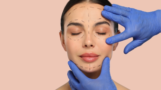 Ženske ruke u plavim rukavicama nežno pozicioniraju lice žene sa iscrtanom konturom za estetski tretman